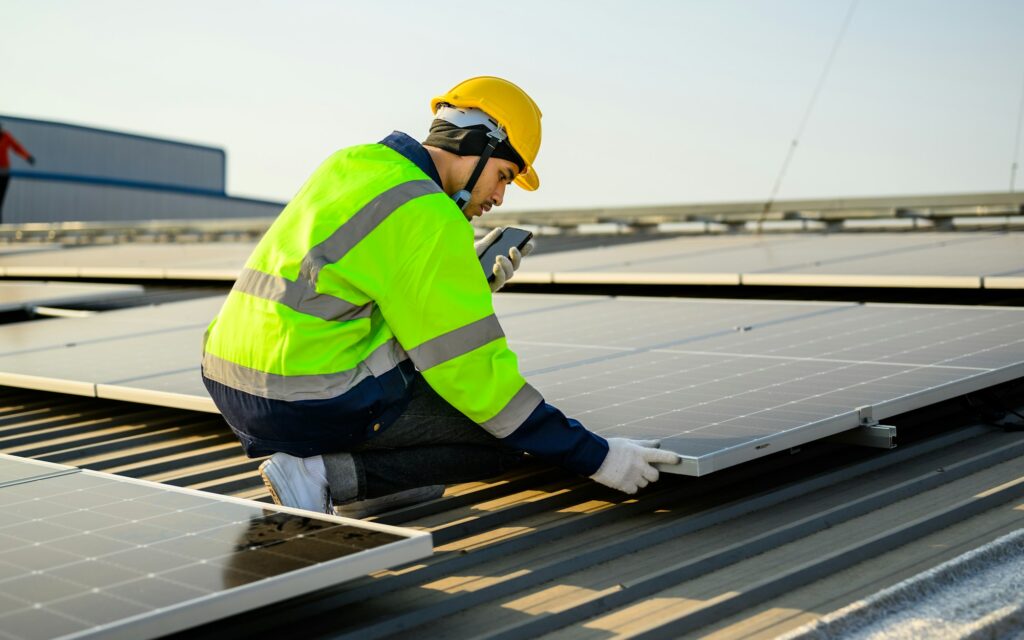 Engineer with helmet working at solar cell power plant with sunset in evening