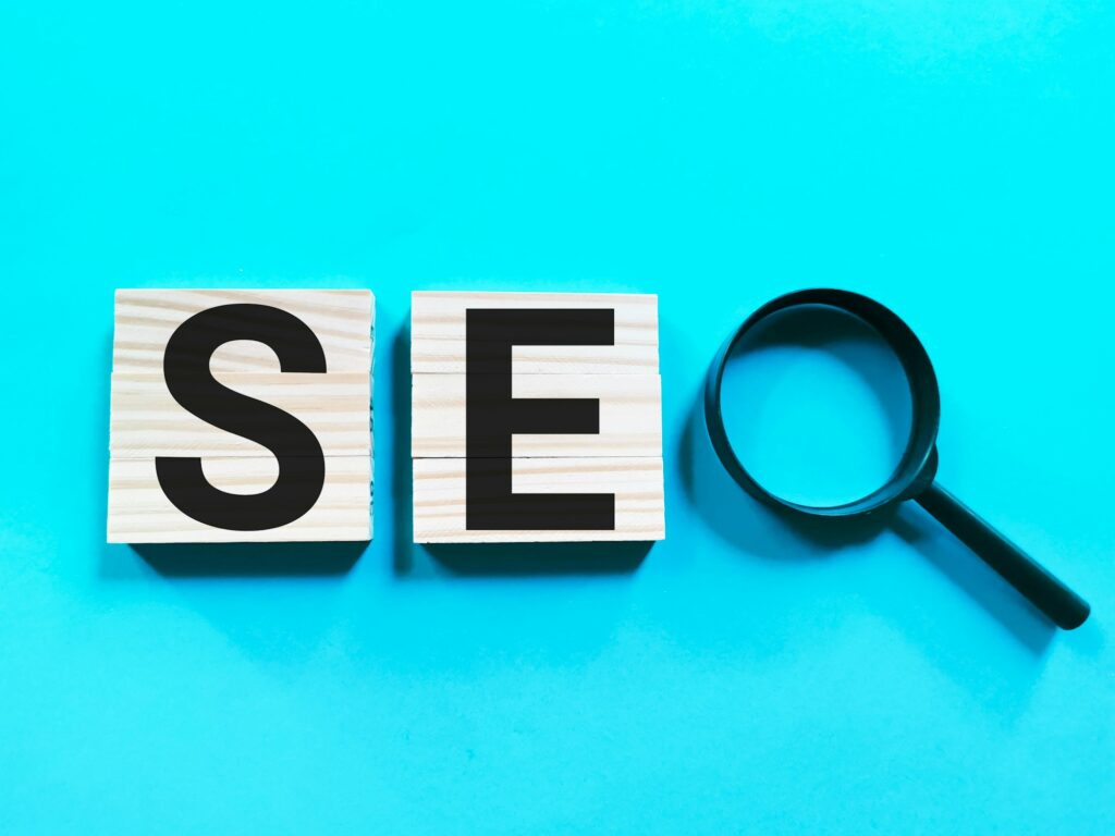 SEO concept on wooden cubes with magnifying glass against blue background.