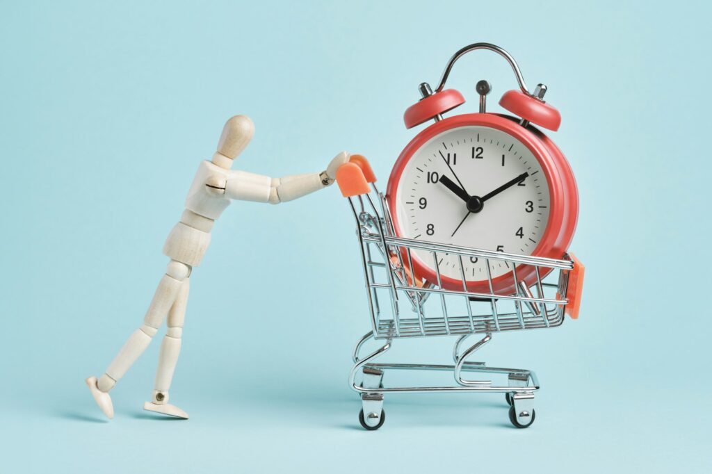 Wooden man pushes a cart with a big red alarm clock.