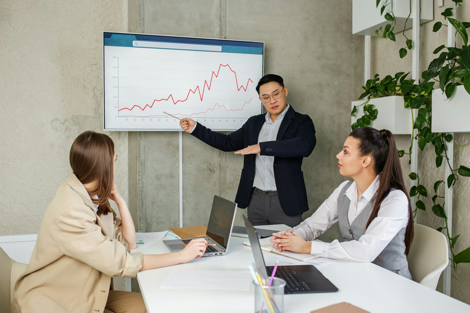 Asian businessman leads presentation with colleagues uses presentation TV with charts.