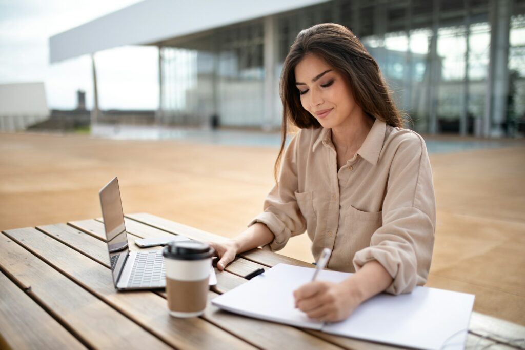 Cheerful pretty young european lady student in casual working at laptop, studying at university with