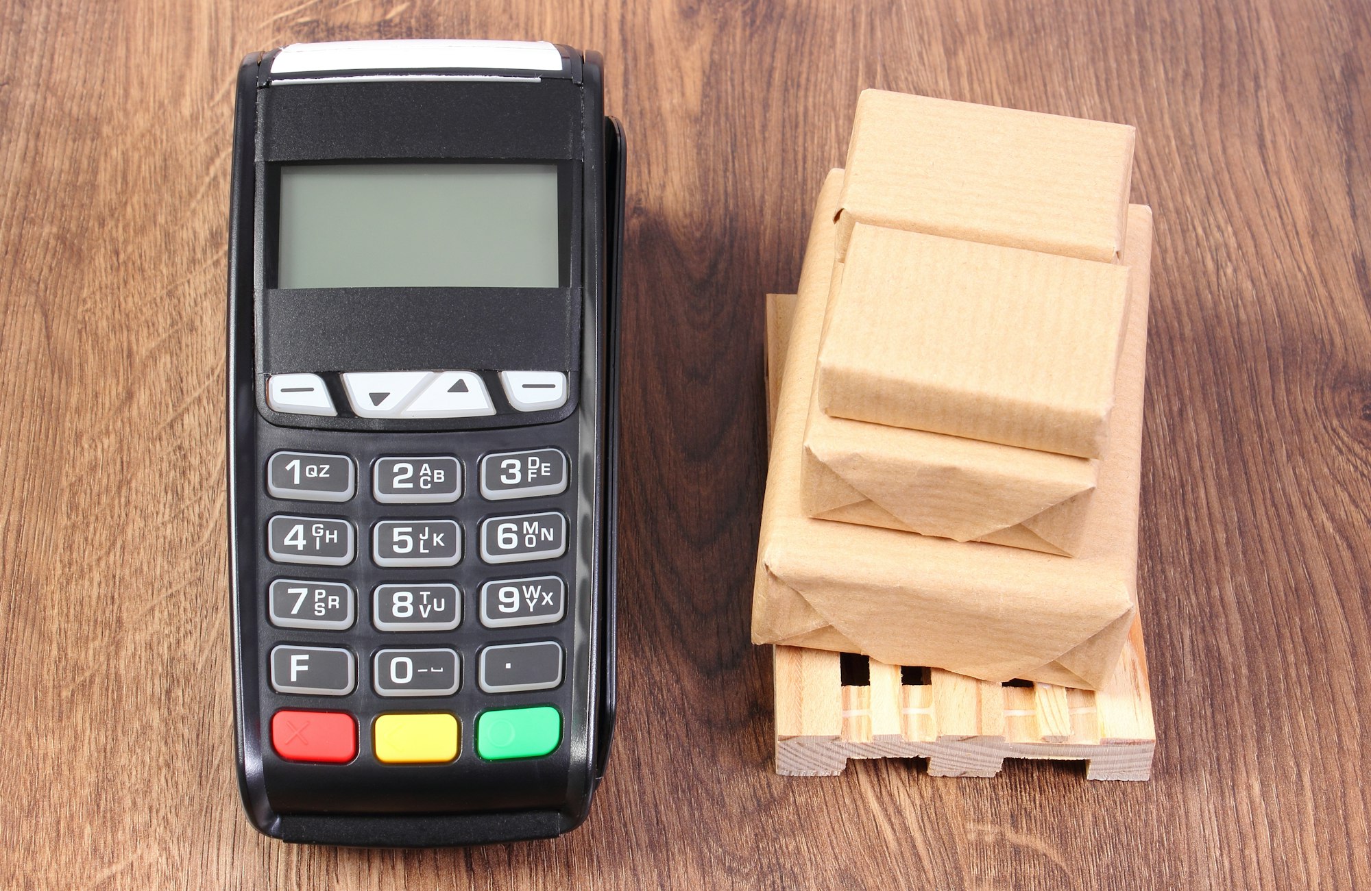 Payment terminal and wrapped boxes on wooden pallet, concept of paying for products and shipping