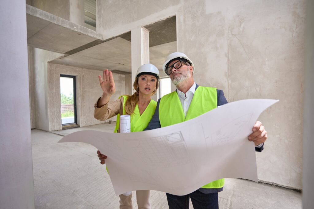 Foreman holds blueprint and discusses it with real estate manager