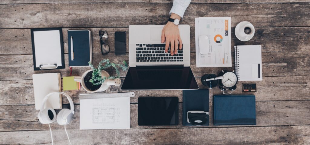 Mix of office supplies and gadgets on a wooden desk