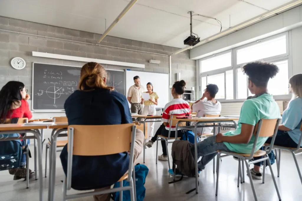 Happy and smiling teen hispanic girl high school student giving a presentation to her multiracial classmates. Copy space.