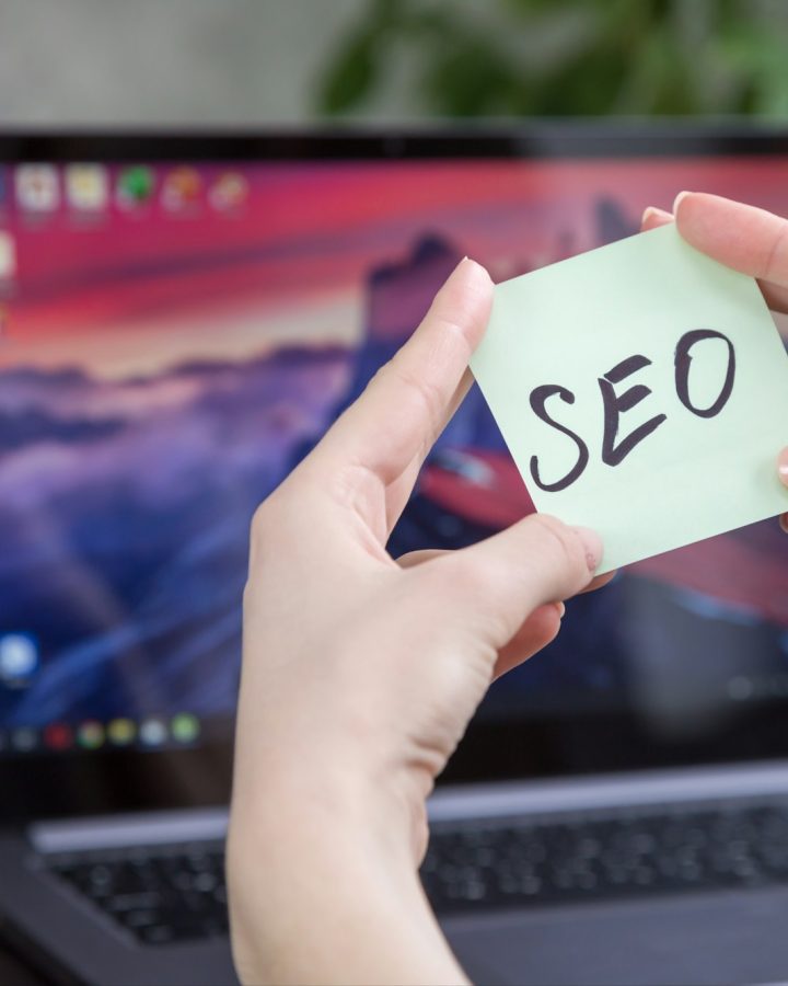 sticker with the inscription SEO in female hands on the background of a laptop