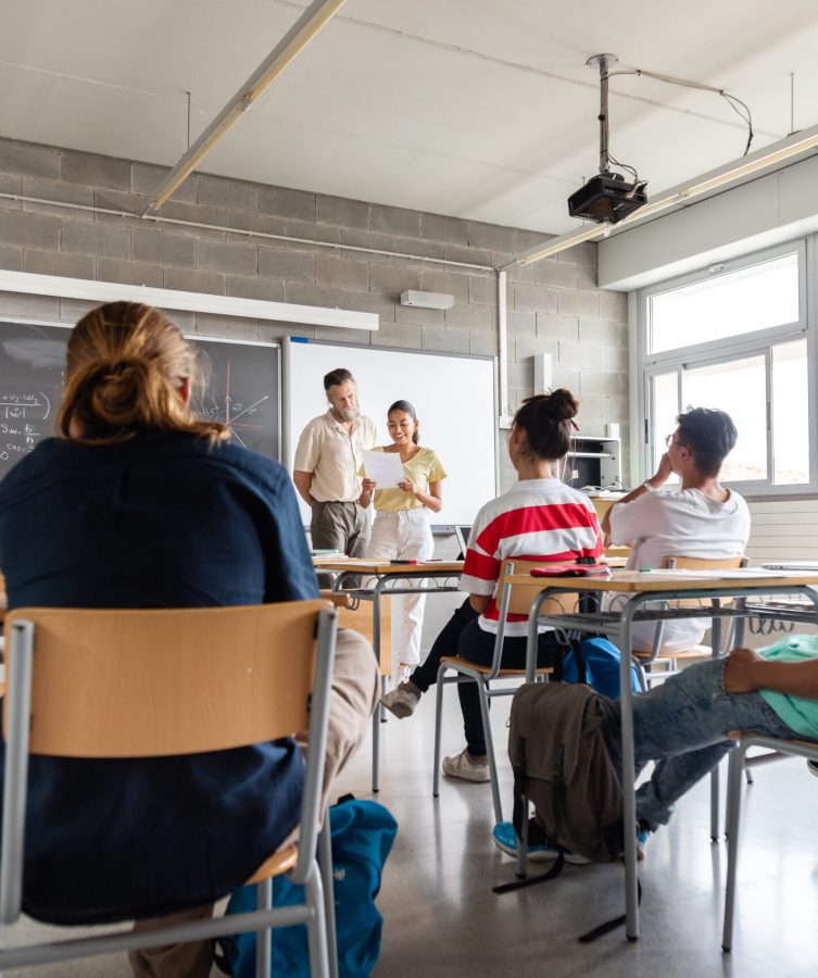 Happy and smiling teen hispanic girl high school student giving a presentation to her multiracial classmates. Copy space. Education concept.